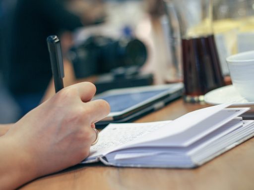 Persoon schrijft meetbare doelen op in een notitieboek aan een bureau