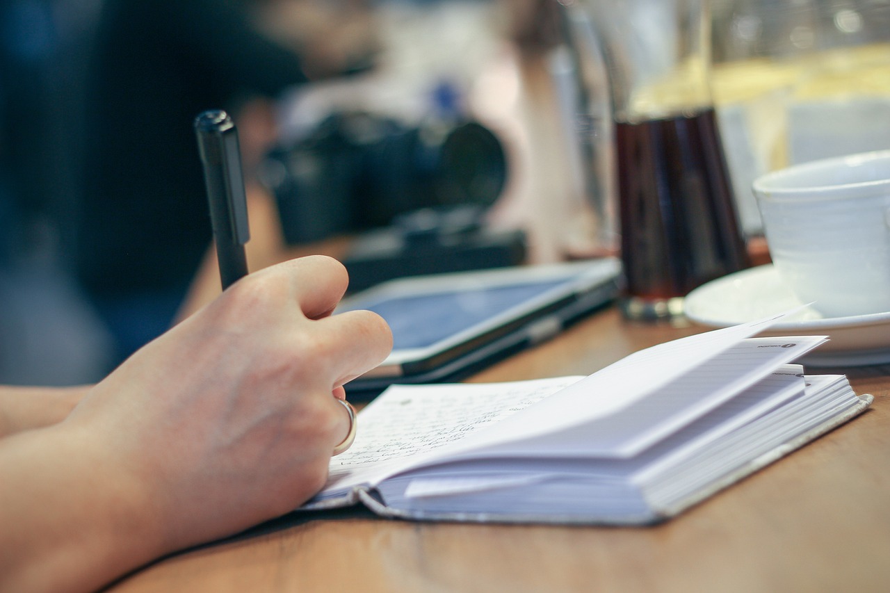 Persoon schrijft meetbare doelen op in een notitieboek aan een bureau