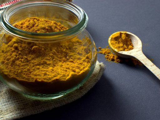 Gelatinepoeder in een houten lepel naast een glas warme vloeistof