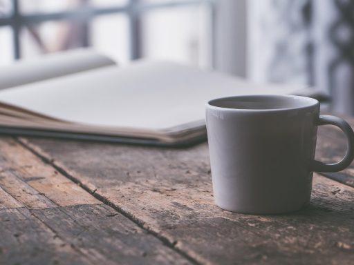 Persoon zit aan tafel en schrijft in een notitieboek, nadenkend over persoonlijk welzijn