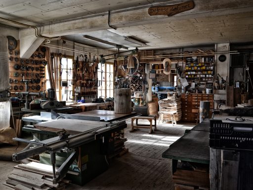 Iemand knap een houten stoel op in een werkplaats met schuurpapier en verf