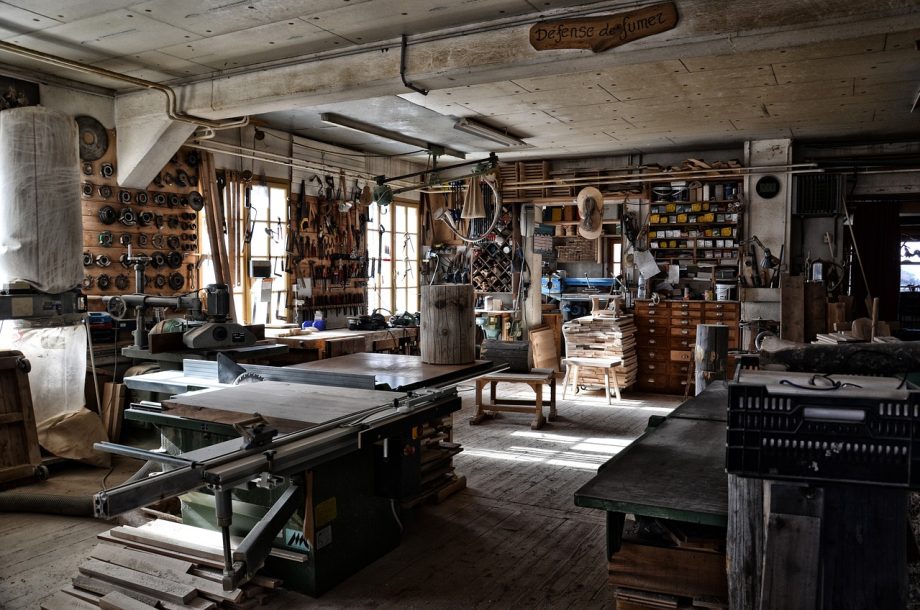 Iemand knap een houten stoel op in een werkplaats met schuurpapier en verf